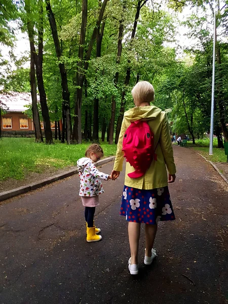母と雨の後、ぬれた夏の日の公園で一緒に歩いて小さな巻き毛幼児少女裏からの眺め — ストック写真