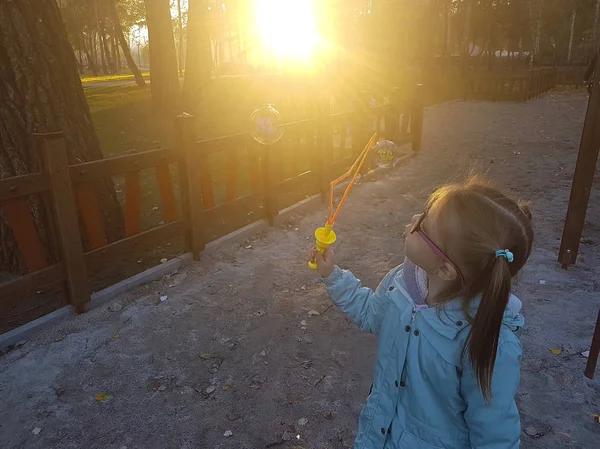 Uma menina soprando bolhas de sabão no parque de verão . — Fotografia de Stock