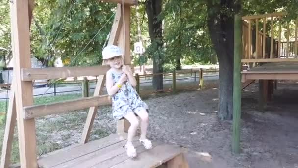 Kleines Mädchen im Abenteuerpark an einem Sommertag. Seilpark. Ausritte in der Natur. Glück und glückliche Kindheit — Stockvideo
