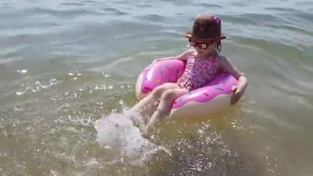 Gyermek a felfújható kör. Boldog lány vízcseppek egy felfújható kör a tengeren. — Stock videók