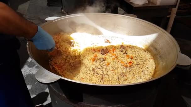 Nationella uzbekiska maträtt pilaff, gröt, Plov, ris med kött. Uzbekiska pilaff i en stor gjutjärn gryta på elden, skivad röd morötter, Berberis, vitlök, röd Chili peppar och ris. Matlagning ris Pilaff — Stockvideo