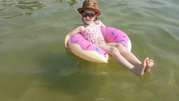 Kind im aufblasbaren Kreis. ein glückliches Mädchen planscht in einem aufblasbaren Kreis im Meer. — Stockvideo