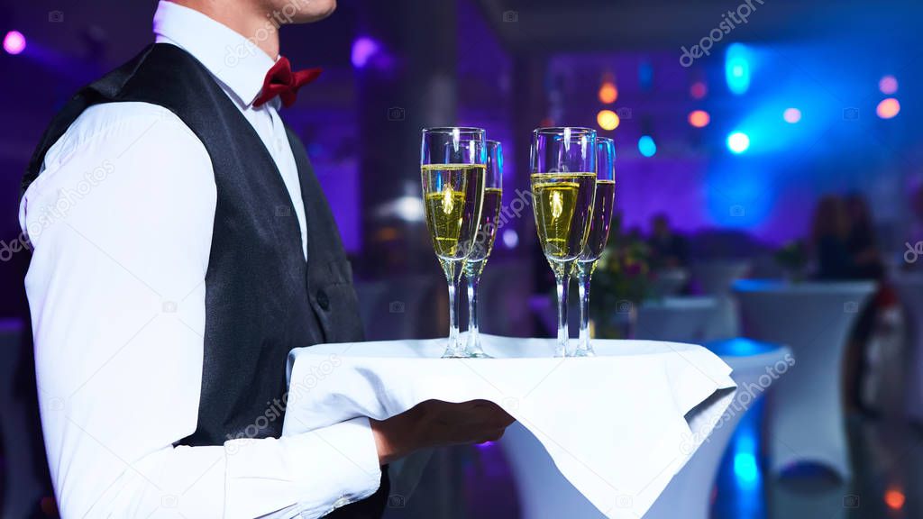 Waiter serving champagne on a tray at party.