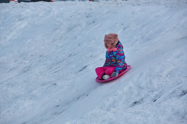 Menina cavalgando em escorregas de neve no inverno — Fotografia de Stock