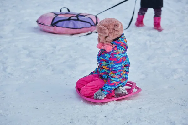 Petite fille chevauchant sur des glissades de neige en hiver — Photo