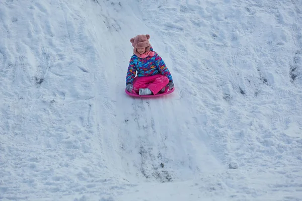 Bambina che cavalca sugli scivoli di neve in inverno — Foto Stock