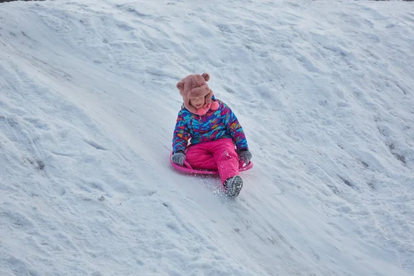 Little girl riding on snow slides in winter time — Stock Photo, Image