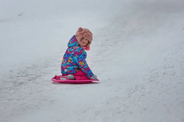 Little girl riding on snow slides in winter time — Stock Photo, Image
