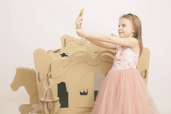 De kleine prinses kijkt in de spiegel. Meisje houdt spiegel. Mode en schoonheid, jeugd. Kind meisje in stijlvolle jurk — Stockfoto