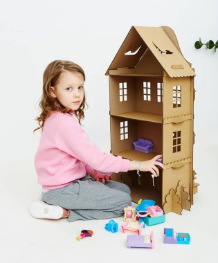 Mutlu kız karton bebek evi ile oynar. Komik güzel çocuk eğleniyor.