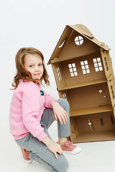 Lycklig flicka leker med kartong docka hus. Rolig härligt barn är att ha kul. — Stockfoto