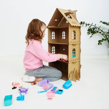 Mutlu kız bebek evini ve bebek ev eşyası ile oynuyor. Komik güzel çocuk eğleniyor.