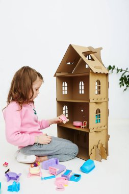 Mutlu kız bebek evini ve bebek ev eşyası ile oynuyor. Komik güzel çocuk eğleniyor.