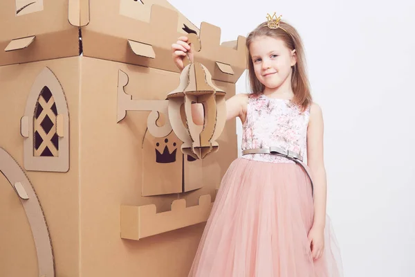 Mała księżniczka w koronie grać z jej karton zamku. Emocje prawdziwego szczęścia dziecka. — Zdjęcie stockowe