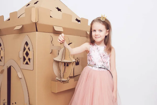 Маленькая принцесса в короне играет со своим картонным замком. Истинное чувство счастья ребенка . — стоковое фото