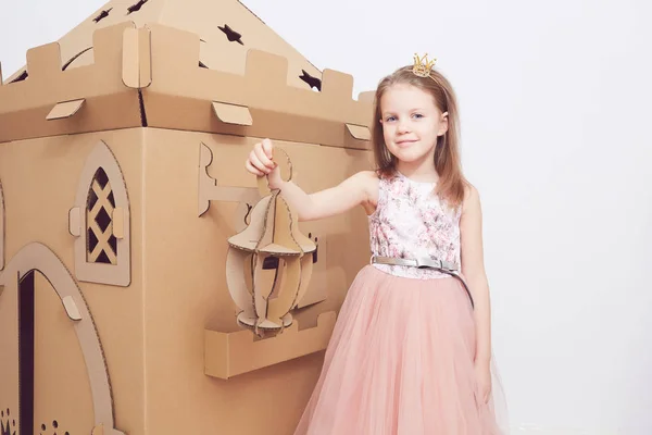 Pequena princesa em coroa jogar com seu castelo de papelão. Emoção verdadeira de felicidade da criança . — Fotografia de Stock