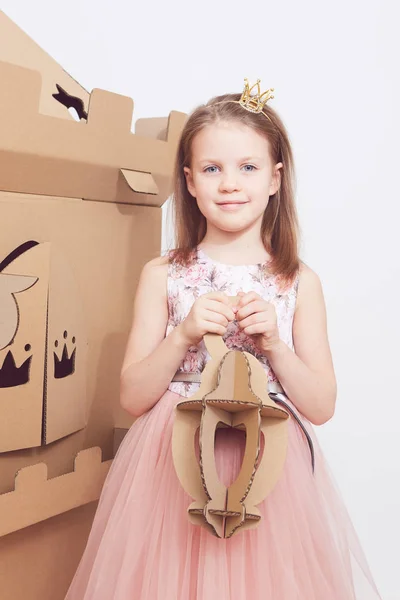 Mała księżniczka w koronie grać z jej karton zamku. Emocje prawdziwego szczęścia dziecka. — Zdjęcie stockowe