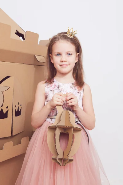 In crown prinsesje spelen met haar kartonnen kasteel. Echte emotie van geluk van het kind. — Stockfoto