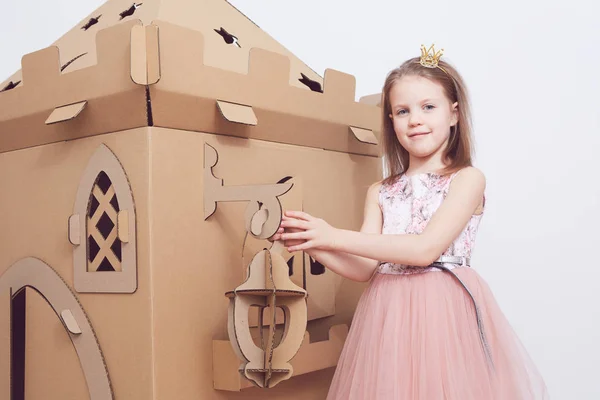 Kleine Prinzessin im Kronenspiel mit ihrer Pappburg. wahre Glücksgefühle des Kindes. — Stockfoto