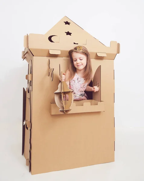 Pequena princesa em coroa jogar com seu castelo de papelão. Emoção verdadeira de felicidade da criança . — Fotografia de Stock