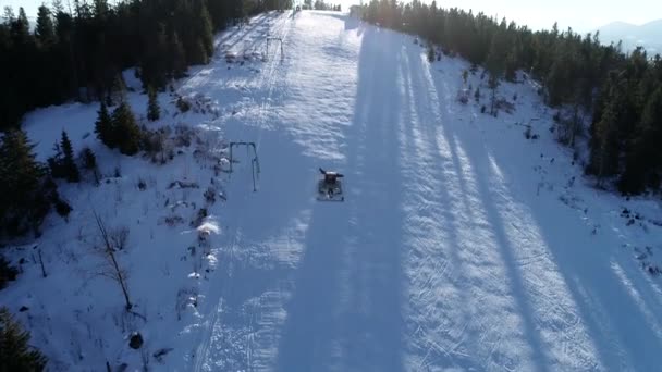 Vackra vinter flyg flyg av drönare över bergen och skidorten. Snowcat började sitt skift, förbereda backarna för nästa dag. 4k. — Stockvideo