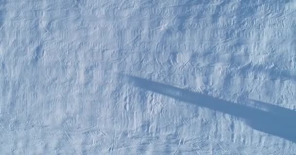 Vista aérea de arriba hacia abajo de un snowcat o un snowgroomer en una pista de esquí en invierno — Vídeos de Stock