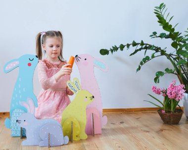 Paskalya 2019 güzel Paskalya süsleri ile elbiseli küçük kız. Büyük Paskalya tavşanları. Bir sürü farklı renkli Paskalya dekor. Çok renkli dekor