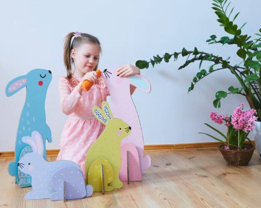 Paskalya 2019 güzel Paskalya süsleri ile elbiseli küçük kız. Büyük Paskalya tavşanları. Bir sürü farklı renkli Paskalya dekor. Çok renkli dekor