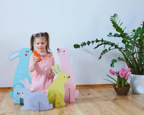 Semana Santa 2019 Hermosa niña en un vestido con decoraciones de Pascua. Grandes conejitos de Pascua. Una gran cantidad de decoración de Pascua de colores diferentes. Decoración multicolor — Foto de Stock