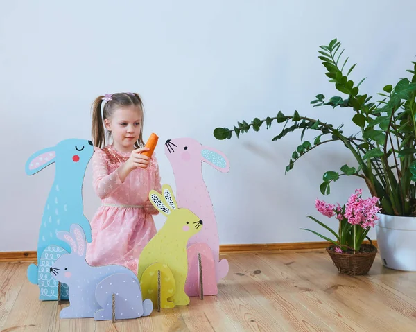Пасха 2019 Красивая маленькая девочка в платье с пасхальными украшениями. Большие пасхальные кролики. Много разнообразного цветового пасхального декора. Разноцветный декор — стоковое фото