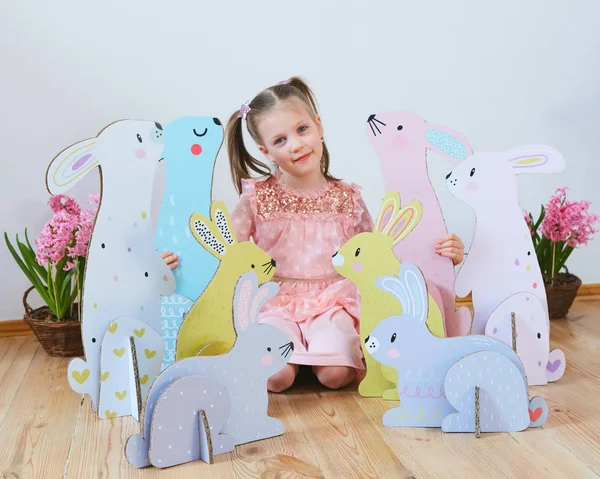 Semana Santa 2019 Hermosa niña en un vestido con decoraciones de Pascua. Grandes conejitos de Pascua. Una gran cantidad de decoración de Pascua de colores diferentes. Decoración multicolor —  Fotos de Stock