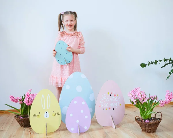 Easter 2019 Beautiful little girl in a dress with Easter decorations. Big Easter eggs and bunnies, colorful place. A lot of different colorful Easter eggs. Multicolored decor — Stock Photo, Image