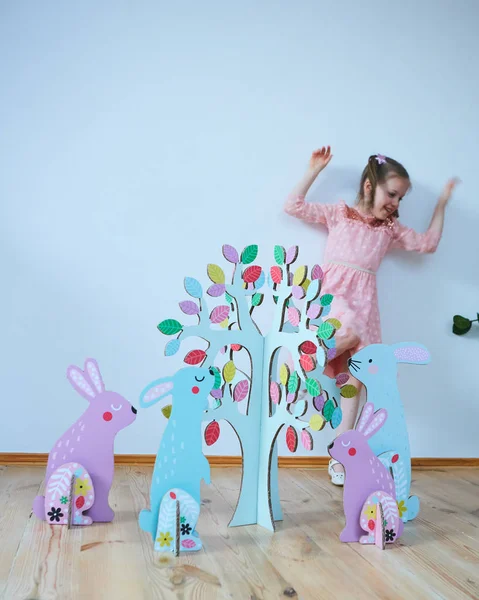 Ostern 2019 schönes kleines Mädchen in einem Kleid mit Osterdekorationen. Große Osterhasen. viele verschiedene bunte Osterdekorationen. Buntes Dekor — Stockfoto