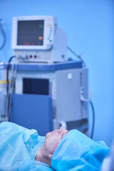 Funzioni vitali funzionali monitorano in una sala operatoria con macchine sullo sfondo, durante un vero intervento chirurgico su un paziente. Concetto di sostenibilità della vita, monitoraggio e anestesia . — Foto Stock