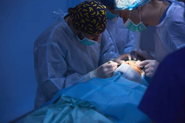 Хирургическая команда, выполняющая операции в современном операционном зале, команда врачей, концентрирующаяся на пациенте во время операции, команда врачей, работающих вместе во время операции в операционной — стоковое фото