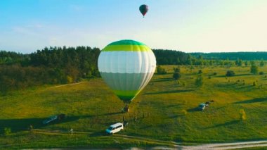 gün batımında kalkış hava balonu , ai balonlar yaz gün batımında çim alanından sinek başlar, yaz akşamı insanlarla sahada hava balonları, uçuş için bir balon hazırlanması.