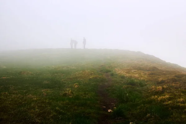 Hombres siluetas en la niebla. Hombres viajando senderismo en las montañas . — Foto de Stock