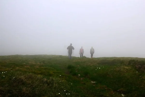 Hombres siluetas en la niebla. Hombres viajando senderismo en las montañas . — Foto de Stock