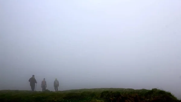 Men silhouettes in fog. Men traveling hiking in mountains.