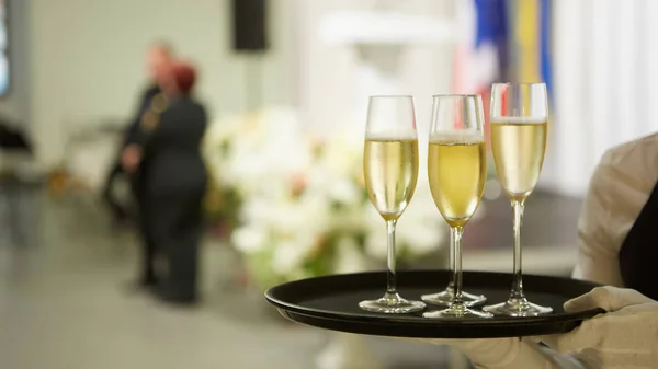 Üç bardak şampanyalı bir tepsi. Garson şampanya bardağı ile bir tepsi tutan — Stok fotoğraf