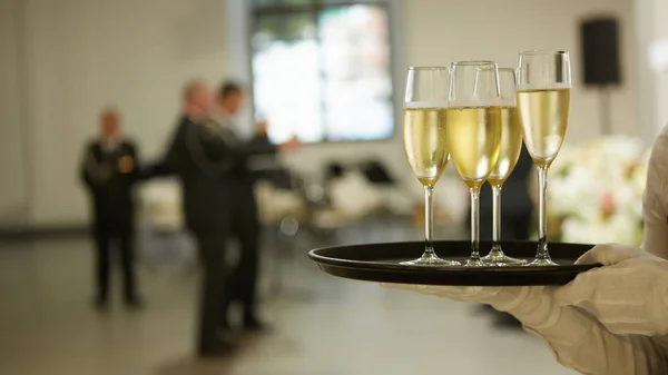 Una bandeja con tres copas de champán. Camarero sosteniendo una bandeja con una copa de champán — Foto de Stock