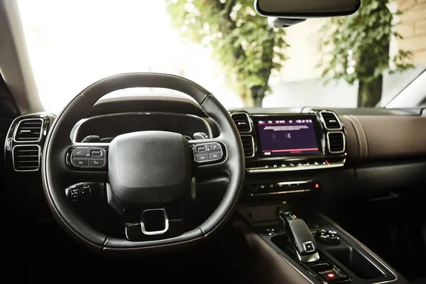 Modern luxury car Interior - steering wheel, shift lever and dashboard. Car interior luxury inside. Steering wheel, dashboard, speedometer, display. Black leather cockpit.