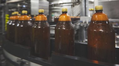 Bira veya gazlı içecek için plastik şişeler konveyör üzerinde hareket ediyor. Sığ Dof. Seçici odaklama.