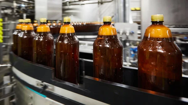 Las nuevas botellas de plástico en la cinta transportadora de la fábrica de cerveza para beber. Proceso de fabricación de agua potable. DOF poco profundo. Enfoque selectivo — Foto de Stock