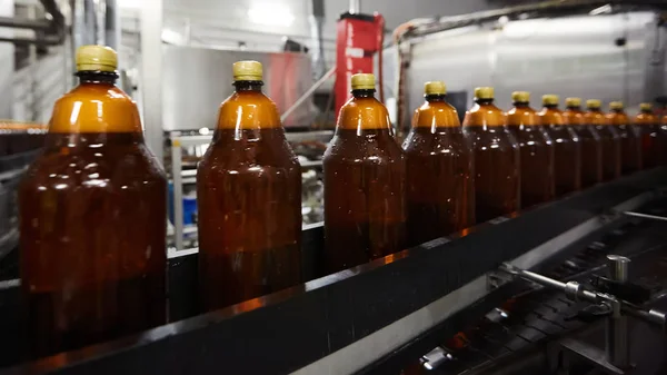 Las nuevas botellas de plástico en la cinta transportadora de la fábrica de cerveza para beber. Proceso de fabricación de agua potable. DOF poco profundo. Enfoque selectivo — Foto de Stock