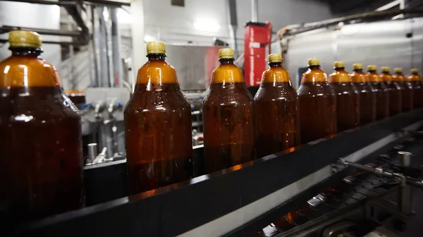 Las nuevas botellas de plástico en la cinta transportadora de la fábrica de cerveza para beber. Proceso de fabricación de agua potable. DOF poco profundo. Enfoque selectivo — Foto de Stock