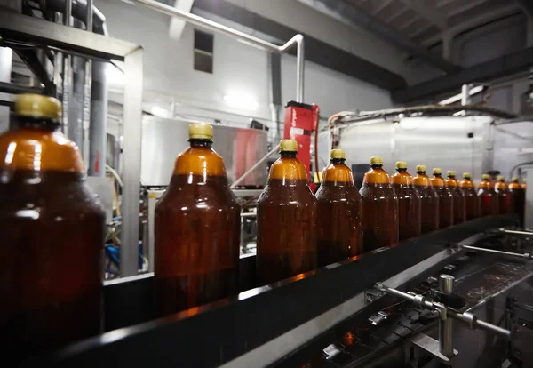 As novas garrafas de plástico na correia transportadora na fábrica de cerveja. Processo de fabricação de água potável. DOF superficial. Foco seletivo — Fotografia de Stock