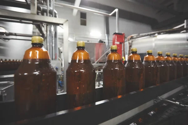 Las nuevas botellas de plástico en la cinta transportadora de la fábrica de cerveza para beber. Proceso de fabricación de agua potable. DOF poco profundo. Enfoque selectivo — Foto de Stock