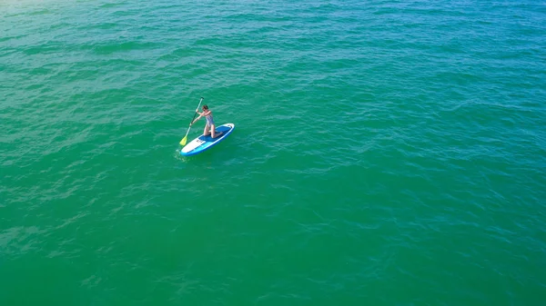 Aerial drone birds eye view of young woman exercising sup board in turquoise tropical clear waters — Stock Photo, Image