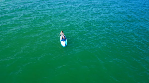 Aerial drone birds eye view of young woman exercising sup board in turquoise tropical clear waters — Stock Photo, Image